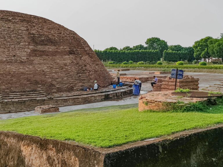 Ancient brick architecture in Bihar, India, with people working on restoration.